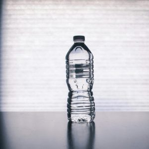 Stylish photo of a clear plastic water bottle on a reflective surface with a soft shadow.