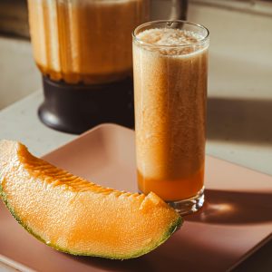 Delicious cantaloupe smoothie with a fresh melon slice, perfect for a healthy snack.