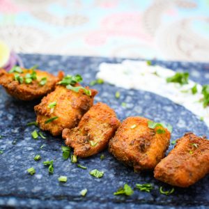 A vibrant plate of Indian fish tikka garnished with herbs, captured in a close-up shot.