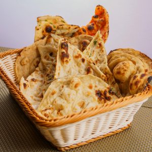 A variety of traditional Indian breads like naan and roti in a wicker basket, perfect for a delicious meal.