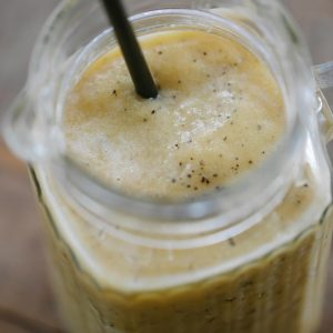 Delicious banana smoothie in a glass jug with black straw, perfect for a refreshing healthy drink.