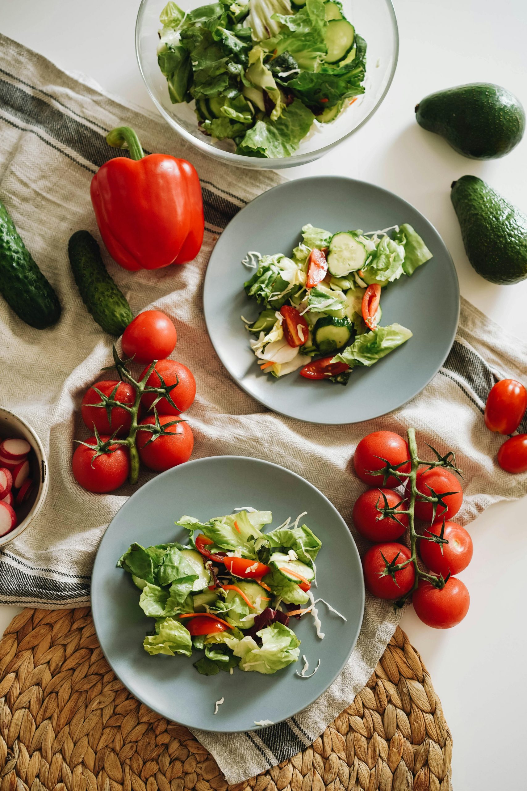 Top view of a vibrant vegetable salad featuring fresh ingredients on plates and a towel.