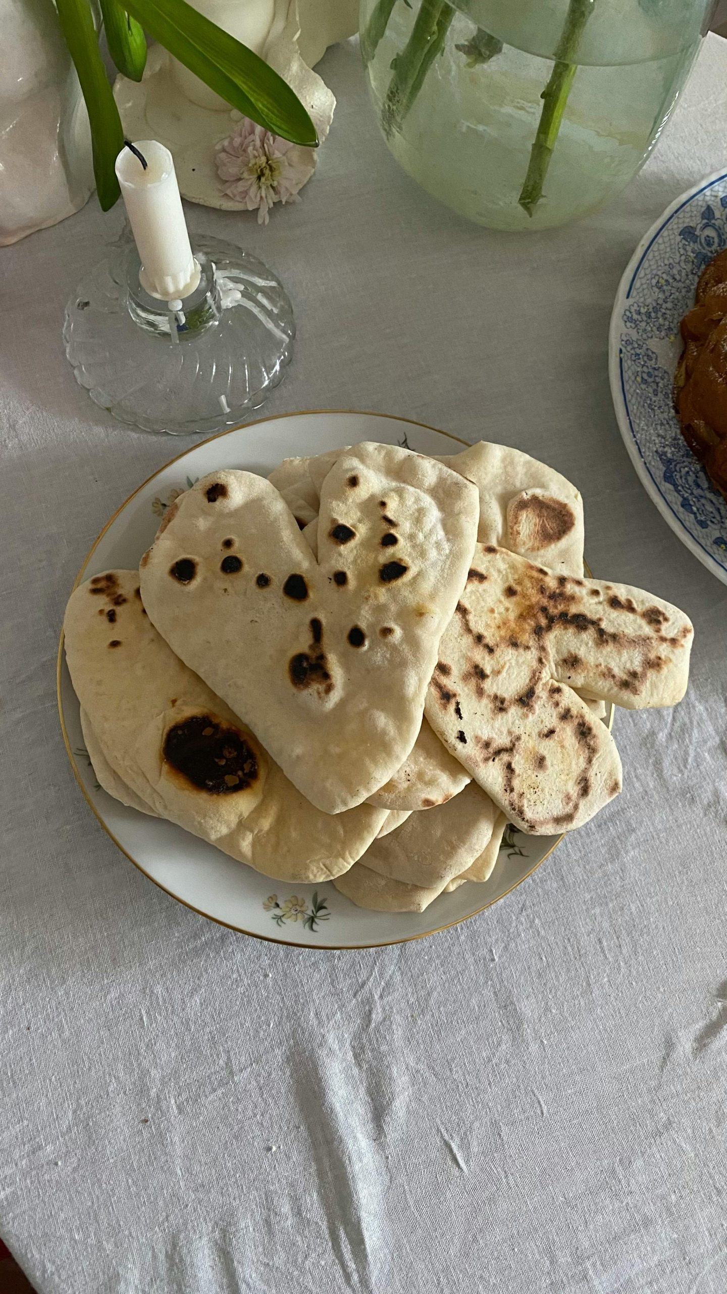 Homemade heart-shaped naan on a decorative plate with a candlelit cozy setup.