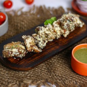 Close-up of delicious Indian Chicken Malai Tikka served with chutney on a wooden tray.