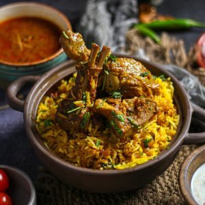Delicious Indian lamb biryani served with spicy curry and yogurt sauce, perfect for a flavorful meal.